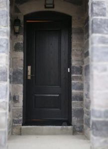 A decorative black wood-style fiberglass entry door.