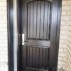 A dark brown fiberglass entry door with a decorative glass insert.