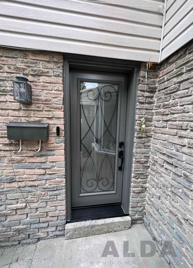 Grey entry door with wrought iron design